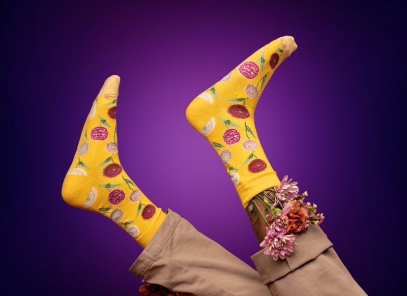 osoba pozira sa veselim čarapama, ljubičasta pozadina